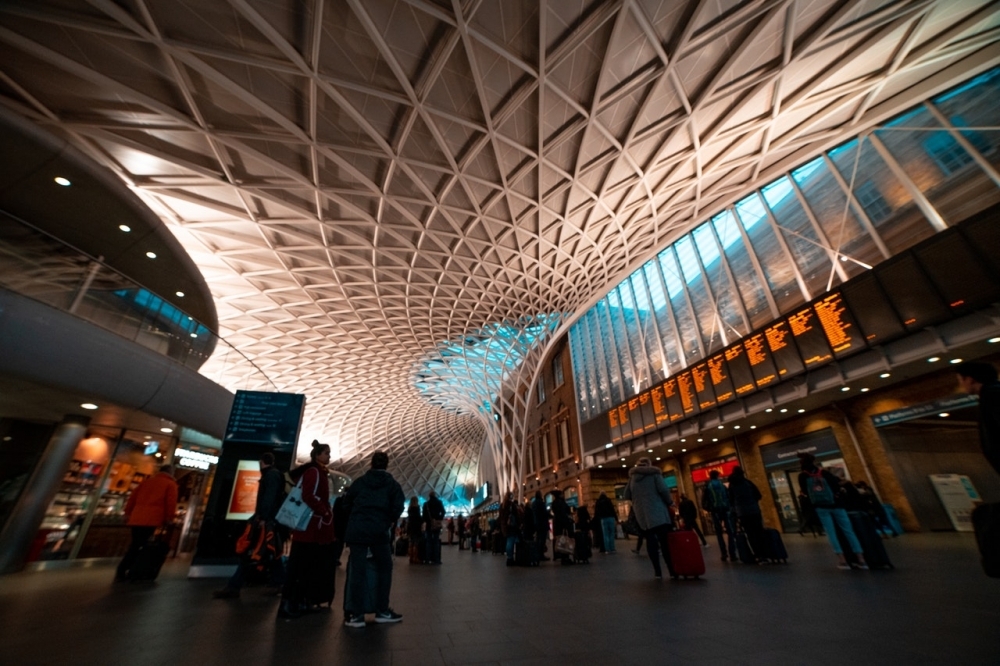 Kings Cross Railway station showing the criss cross pattern curved ceiling and people watching the arrivals board.