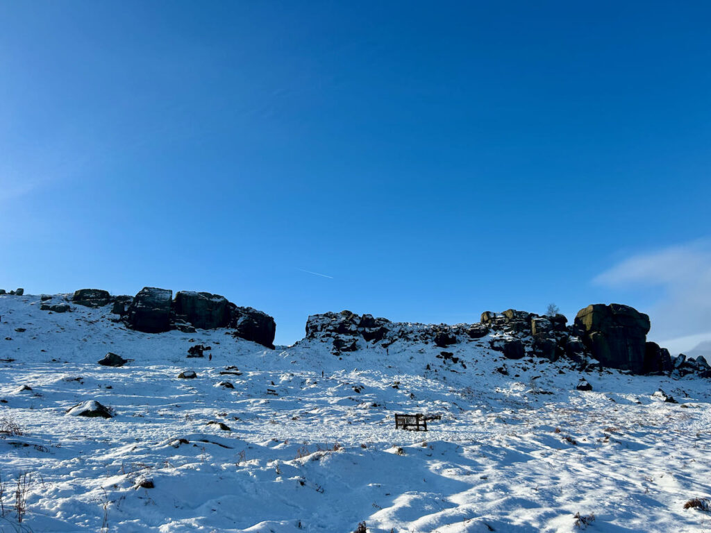 A snow covered Cow and Calf rocks on Ilkley Moor set against a bright blue winter sky